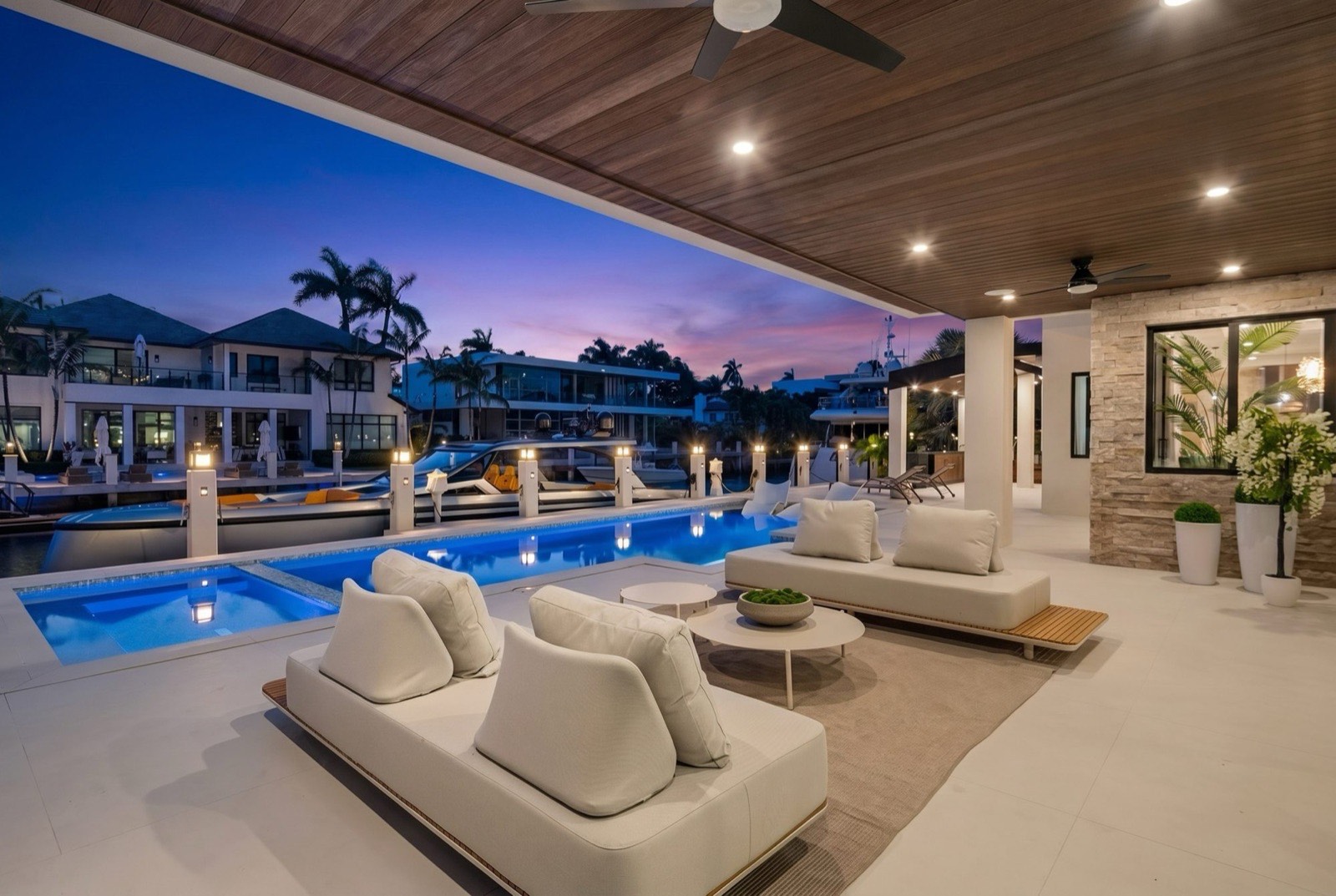 Covered lanai with lounge seating looking over the pool to the water